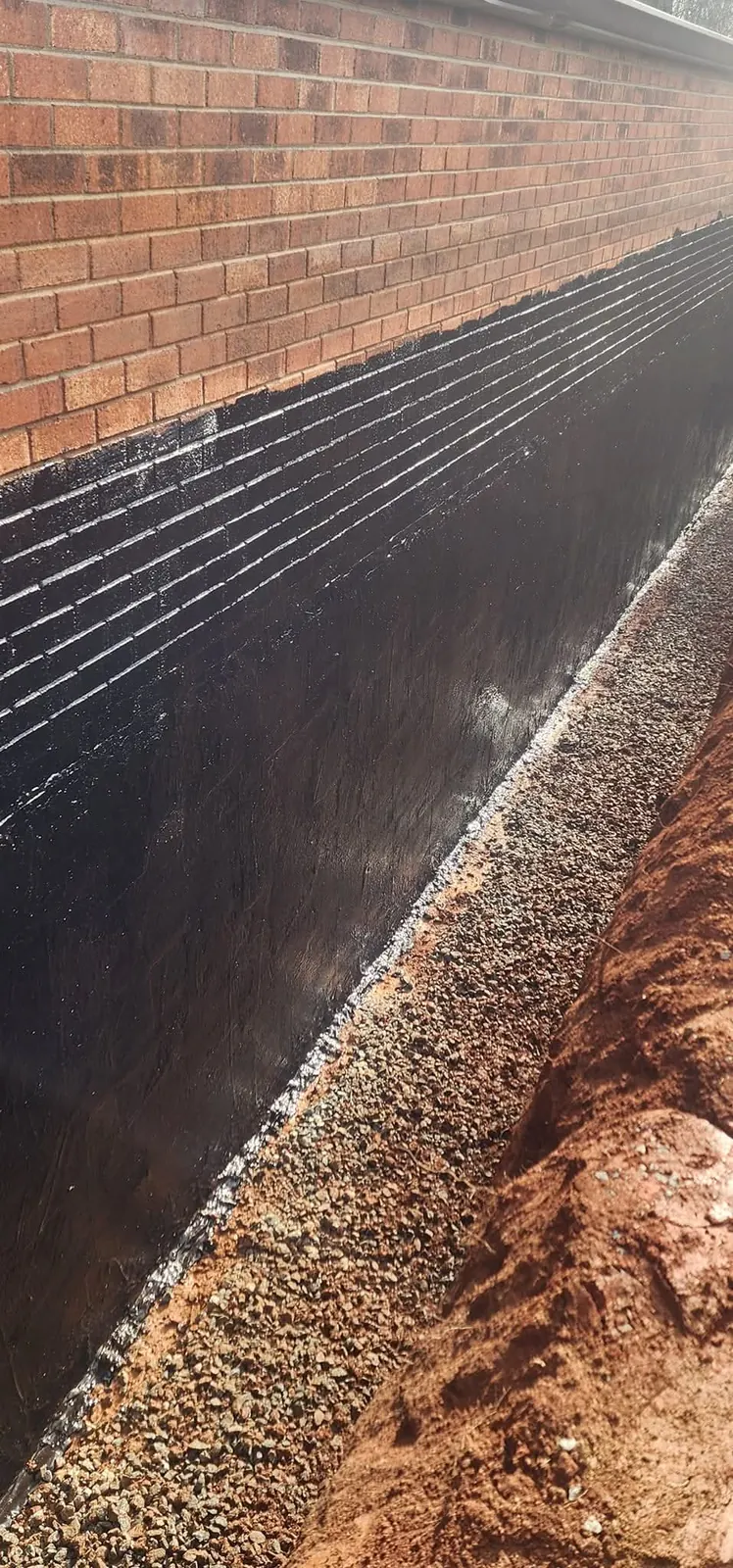 A foundation trench with waterproofing and stone backfill for drainage &mdash; Little Acres Grading, Granite Falls NC
