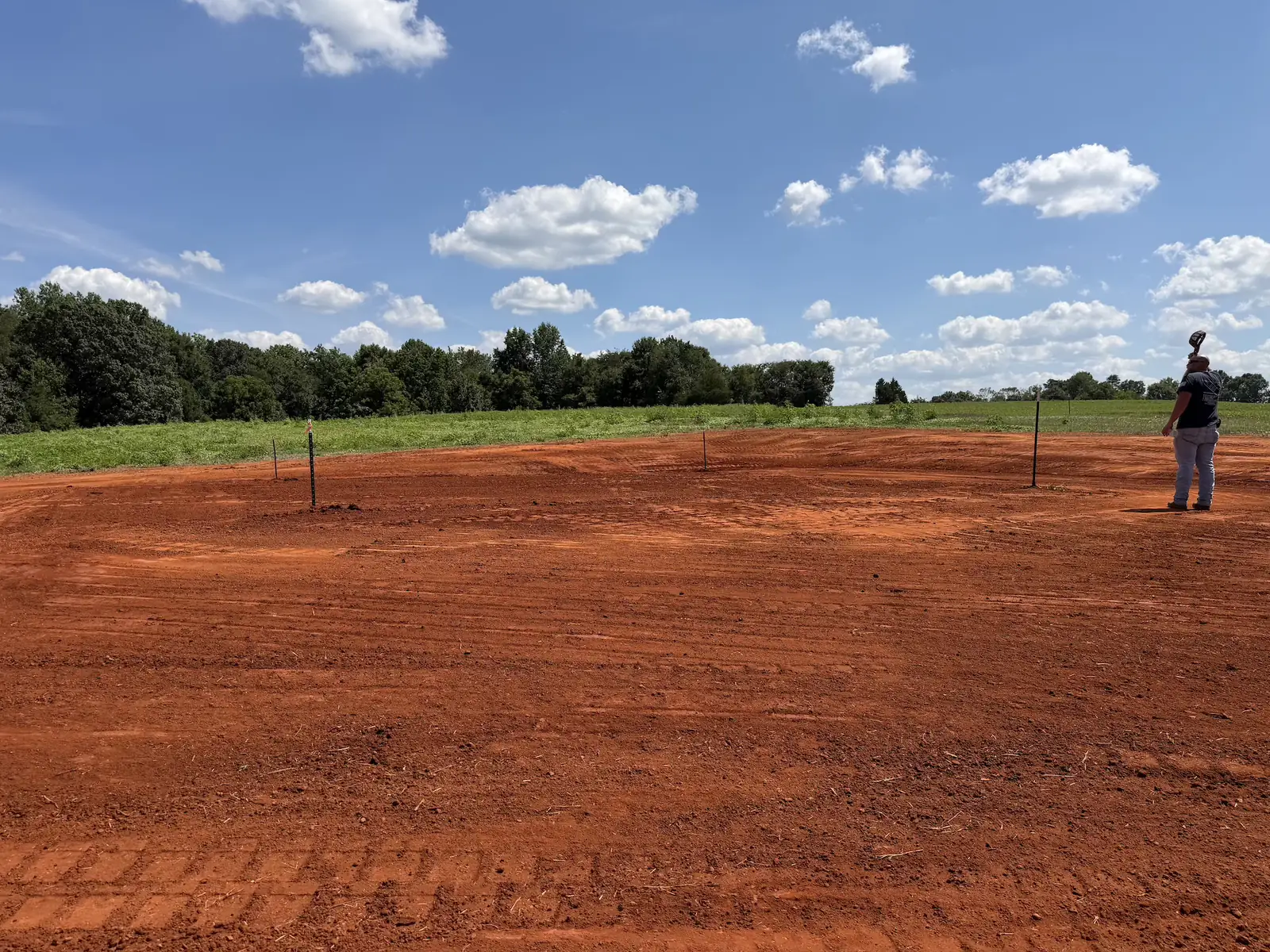 A building pad cut and staked out on open pasture ground &mdash; Little Acres Grading