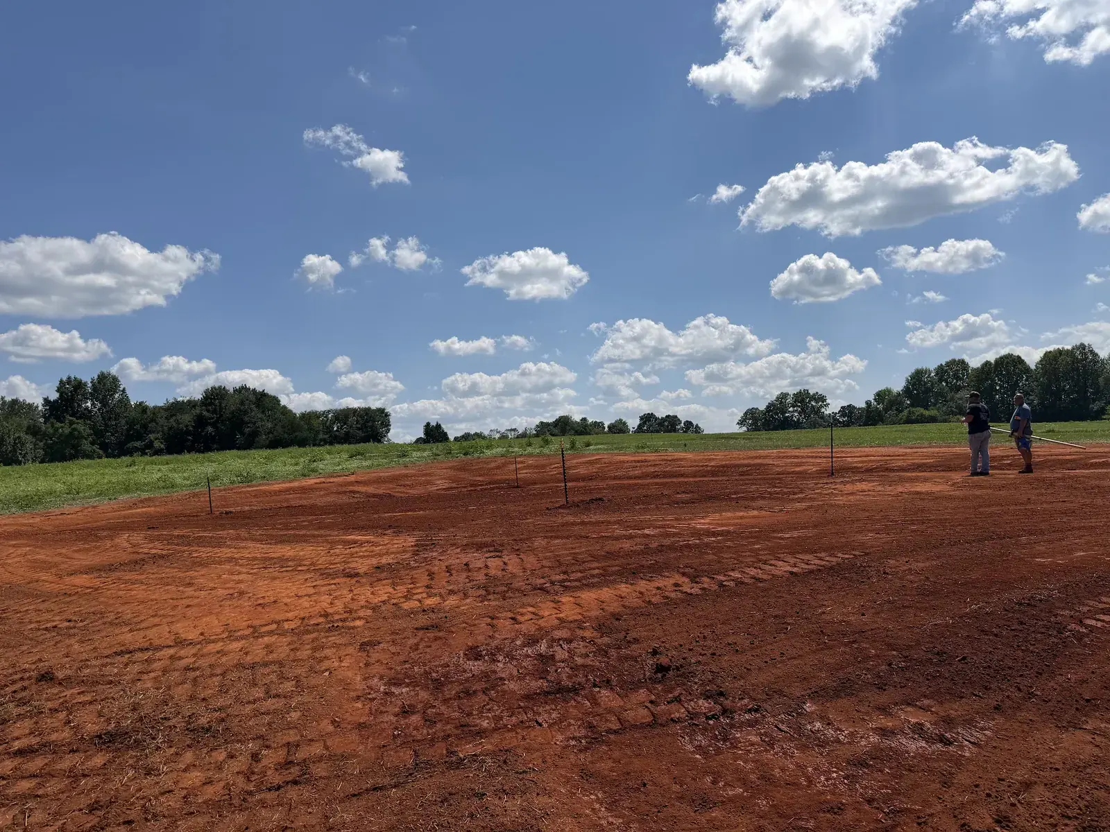 A house pad graded to elevation with corner stakes set for the builder &mdash; Little Acres Grading