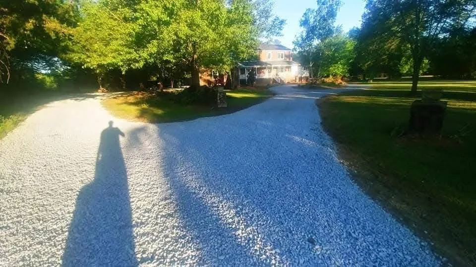 A freshly stoned driveway running along a shaded tree line &mdash; Little Acres Grading