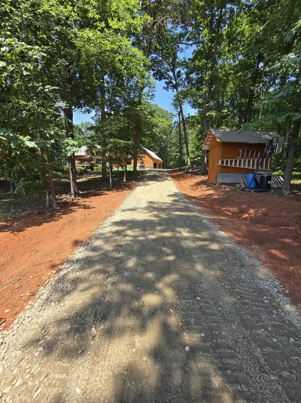 A gravel drive graded up through a wooded lot to a cabin &mdash; Little Acres Grading