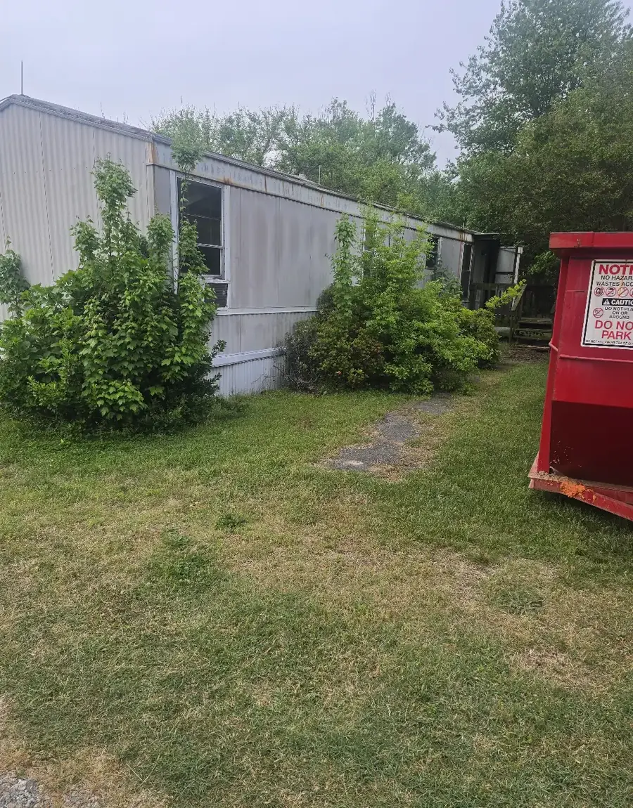 An abandoned mobile home grown over with brush before demolition &mdash; Little Acres Grading