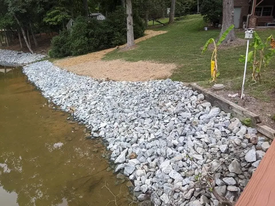 A lake bank stabilized with graded rip-rap above the waterline &mdash; Little Acres Grading