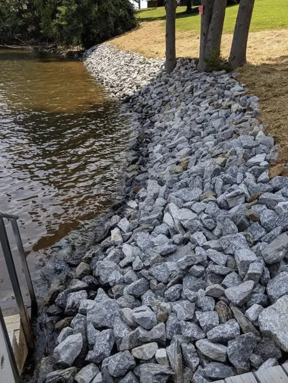 Rip-rap set tight along a lake shoreline beside a dock &mdash; Little Acres Grading