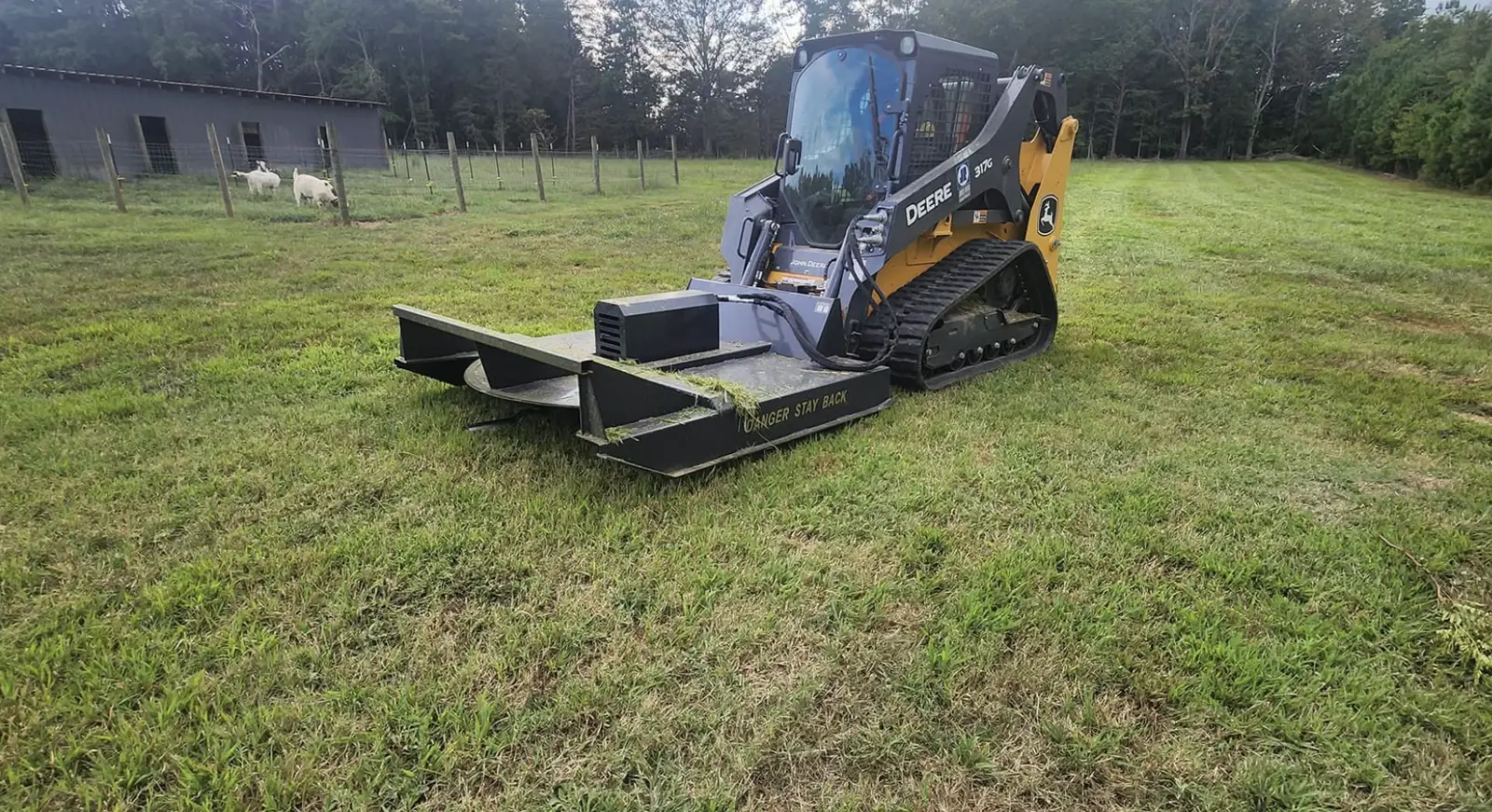 A skid steer with a brush cutter attachment clearing pasture &mdash; Little Acres Grading